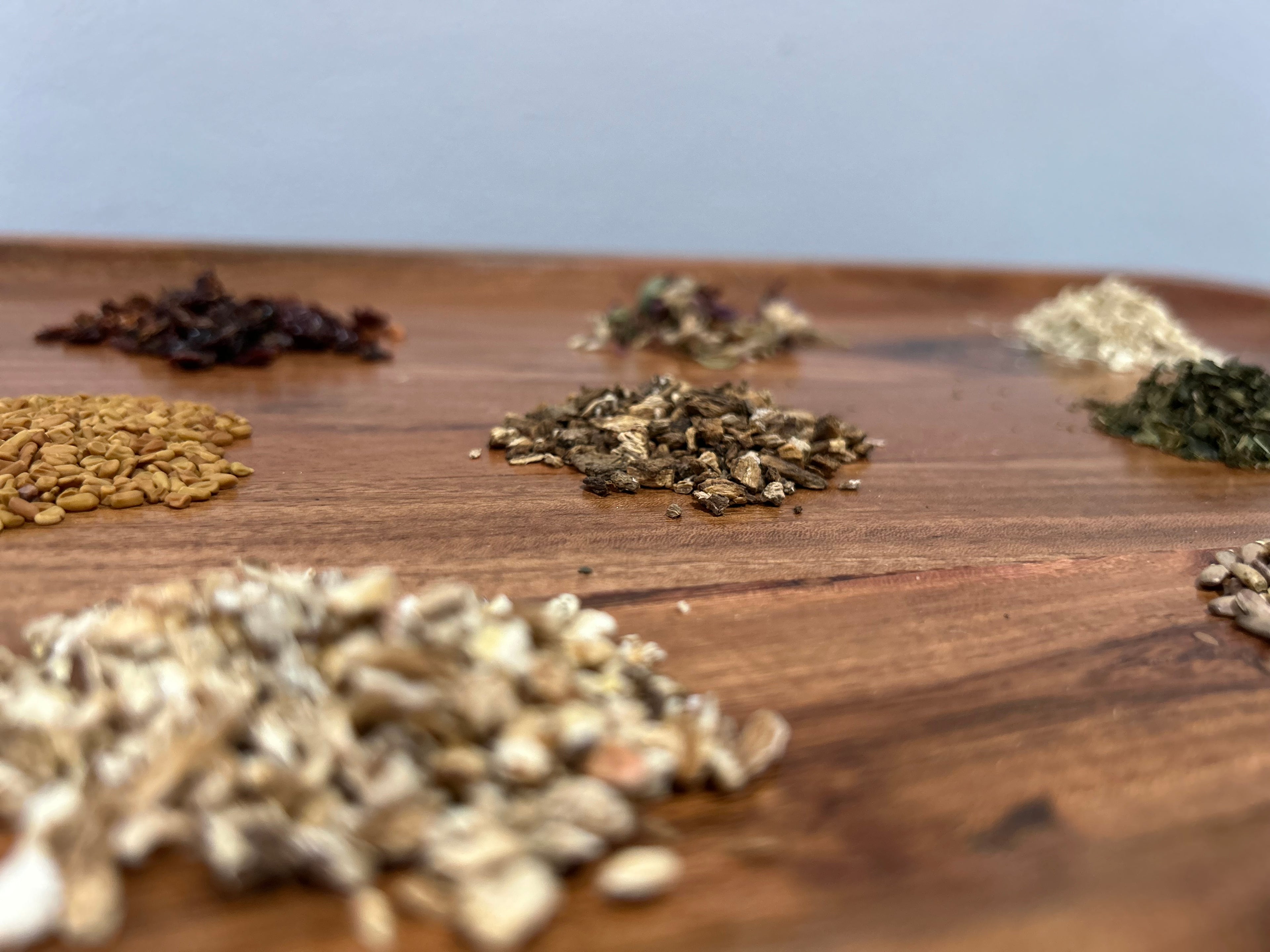 Various types of dried herbs on a wooden surface with a white background
